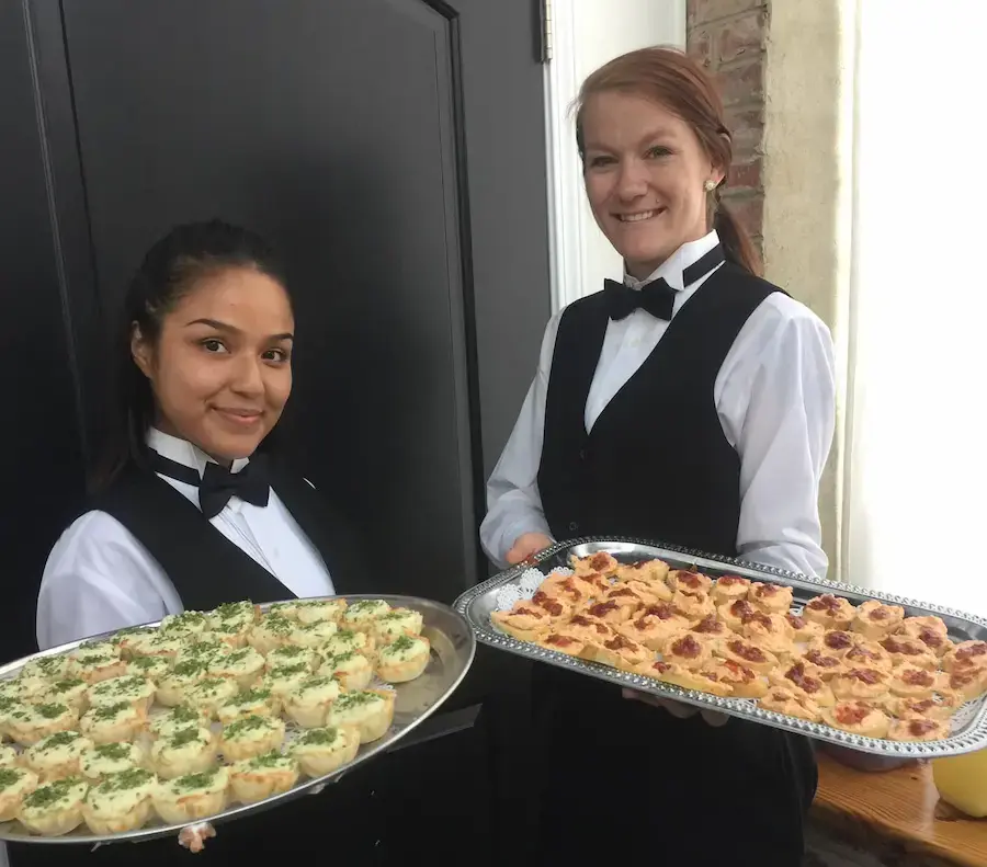 Two women holding trays of appetizers